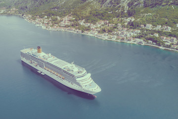 Top view of a beautiful cruise liner floating by the city. Toned