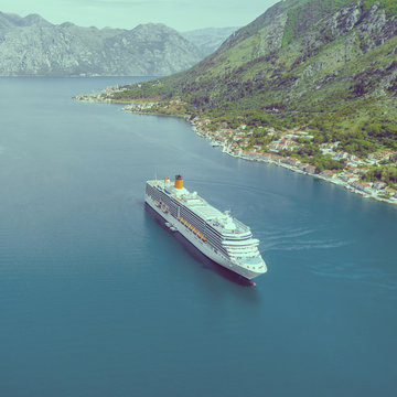 Beautiful white cruise ship floating near the city in the mountains