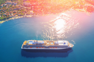 Top view of a beautiful cruise liner and the city at sunset - obrazy, fototapety, plakaty