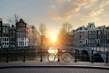 Tuinposter Amsterdam Fietsen langs een brug over de grachten van Amsterdam, Nederland. Fiets is de belangrijkste vorm van vervoer in Amsterdam, Nederland.