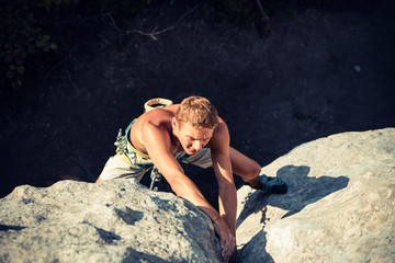 Men climbs a rock and makes difficult move