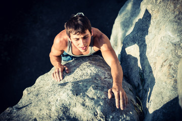 Men climbs a rock and find next holds on a rock