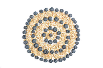 Heap of oat flakes in circle shape. Tropical abstract background with rolled oats. Berries on the white background.