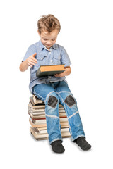 Boy with a book sitting on a pile of books on a white background. Isolated