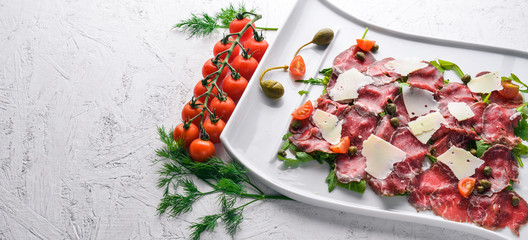 Carpaccio with meat and vegetables. Italian cuisine. On a wooden background. Top view. Free space...