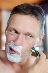 Handsome man shaving his beard.