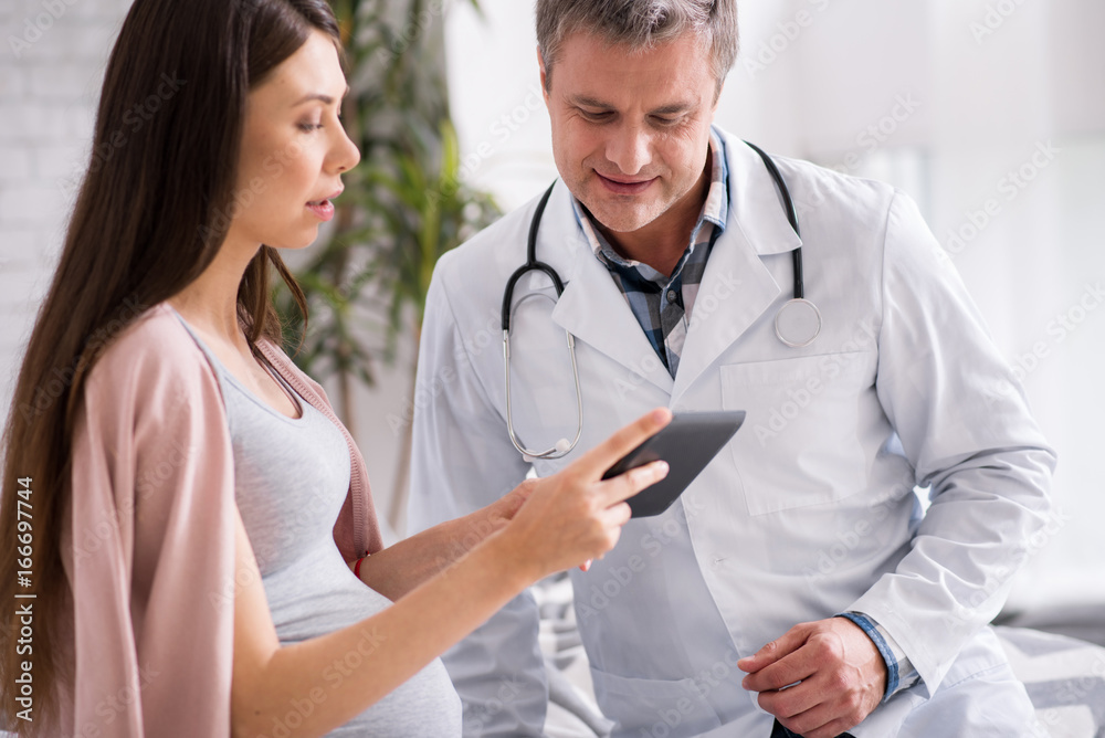 Wall mural Attentive woman showing pictures to her doc