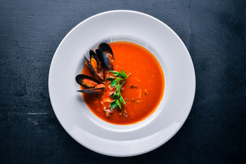 Tomato and seafood creamy soup with mussels. On a wooden background. Top view. Free space for your text.