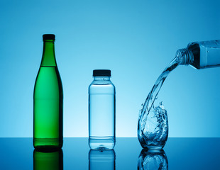 Bottle with creative splashing water in the glass