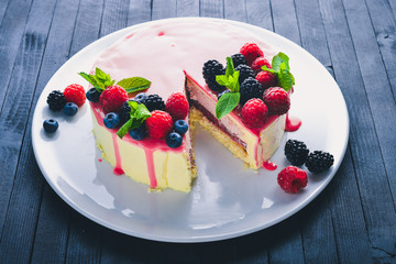 Cake with butter and fresh berries and fruits. Dessert. On a wooden background. Top view. Free space for your text.