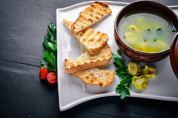 Broth from ravioli and herbs. Italian cuisine. On a wooden background. Top view. Free space for your text.