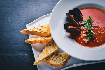 Tomato and seafood creamy soup with mussels. On a wooden background. Top view. Free space for your text.