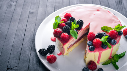 Cake with butter and fresh berries and fruits. Dessert. On a wooden background. Top view. Free space for your text.