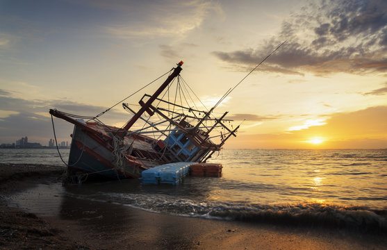 Abandoned shipwreck of wood fishing boat on beach at Twilight time