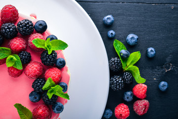 Cake with butter and fresh berries and fruits. Dessert. On a wooden background. Top view. Free space for your text.