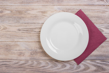 Top view of clean empty plate on wooden tabletop with napkin