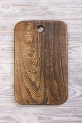 Cutting board on white wooden table, top view
