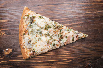 Piece of pizza on a brown wooden background, top view