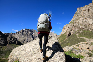 successful woman with backpack hiking in mountains