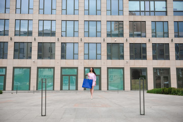 Beautiful happy girl goes shopping in the city.