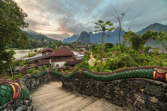 Traditional lao village with temple stairs and mountain background near Vang Vieng, Laos.
