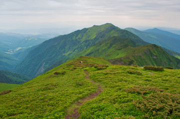 Small figures of travelers descending down a winding path leading to majestic mountain peak and...