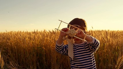 Happy kid with a toy airplane at sunset in a wheat field - Powered by Adobe
