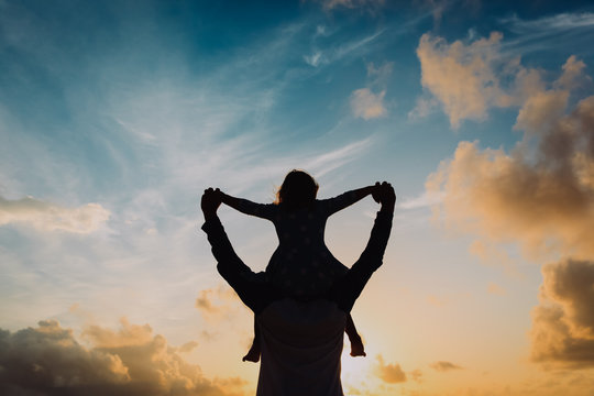 Father and little daughter silhouettes play at sunset