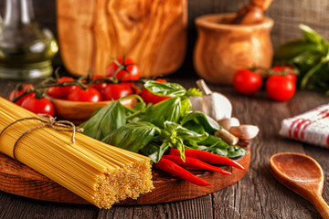 Products for cooking - pasta, tomatoes, garlic, pepper, and basil.