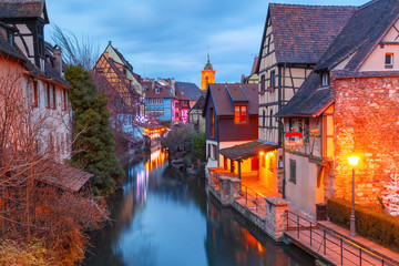 Traditional Alsatian half-timbered houses, church and river Lauch in Petite Venise or little Venice, old town of Colmar, decorated and illuminated at christmas time, Alsace, France - obrazy, fototapety, plakaty