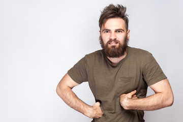 Obraz premium Portret śmieszne szalony brodaty mężczyzna z ciemnozieloną koszulką na jasnoszarym tle. strzał studio. .