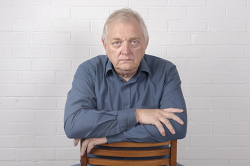 Obraz premium Serious mature man with a white brick background and copy space 