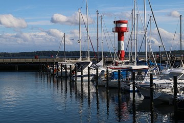 malerischer Hafen mit Booten und Leuchtturm im Ostseebad Eckernförde, blauer Himmel und Wolken 