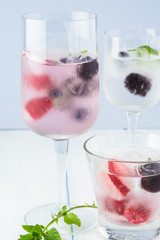 Glasses of water with ice cubes with fresh berries.