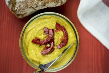 Authentic homemade curry hummus with red capsicum garnish and a silver serving spoon