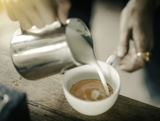 Coffee maker pouring the milk for make latte art