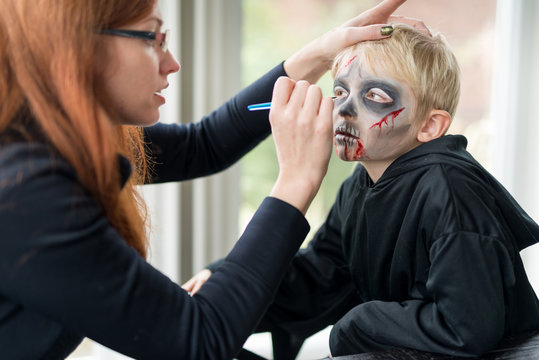 Mother Applying Scary Halloween Costume Make Up for Boy