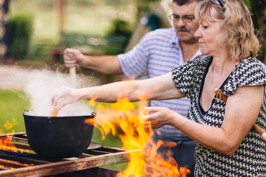 Mature Man And Woman Preparing Food On Bbq