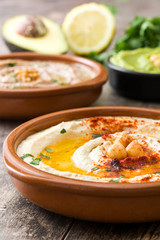 Different hummus bowls. Chickpea hummus, avocado hummus and lentils hummus on wooden table

