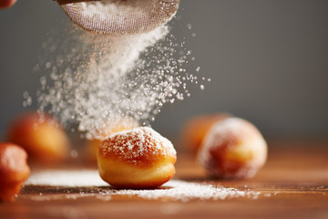 Pouring icing sugar on donut holes