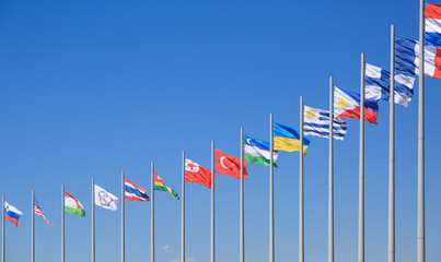 Flags of many countries flutter on the background of the blue sky in sunny day