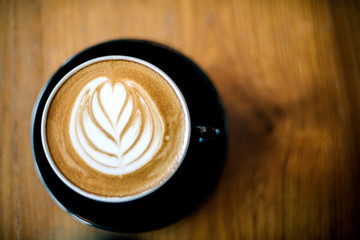 Latte art on dark grained wood top view