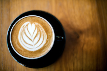 Latte art on dark grained wood top view