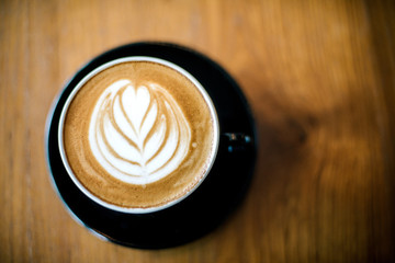 Latte art on dark grained wood top view