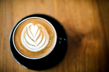 Latte art on dark grained wood top view