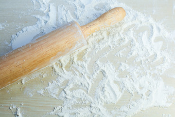 Baking background with the rolling pin with flour. On the bright surface (table) Free space for text . Top view.