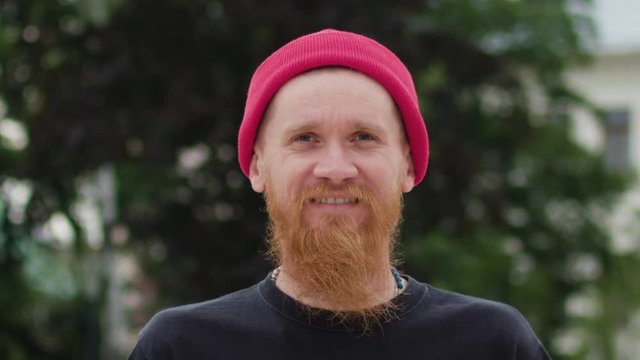 Young readhead hispter with beard and moustaches in jeans and T-shirt laughs suddenly. Outdoor. Cloudy. Medium. Stabilised. Portrait