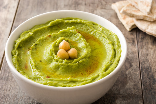 Avocado hummus in bowl on wooden table

