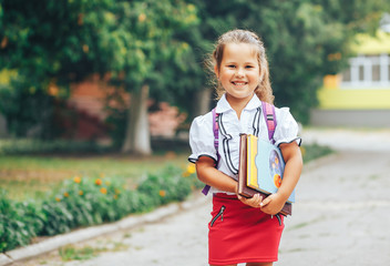 A schoolgirl of junior classes of Asian appearance with a book in her hands