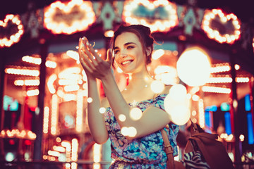 Beautiful young woman smiling and talking garlands of lights at city